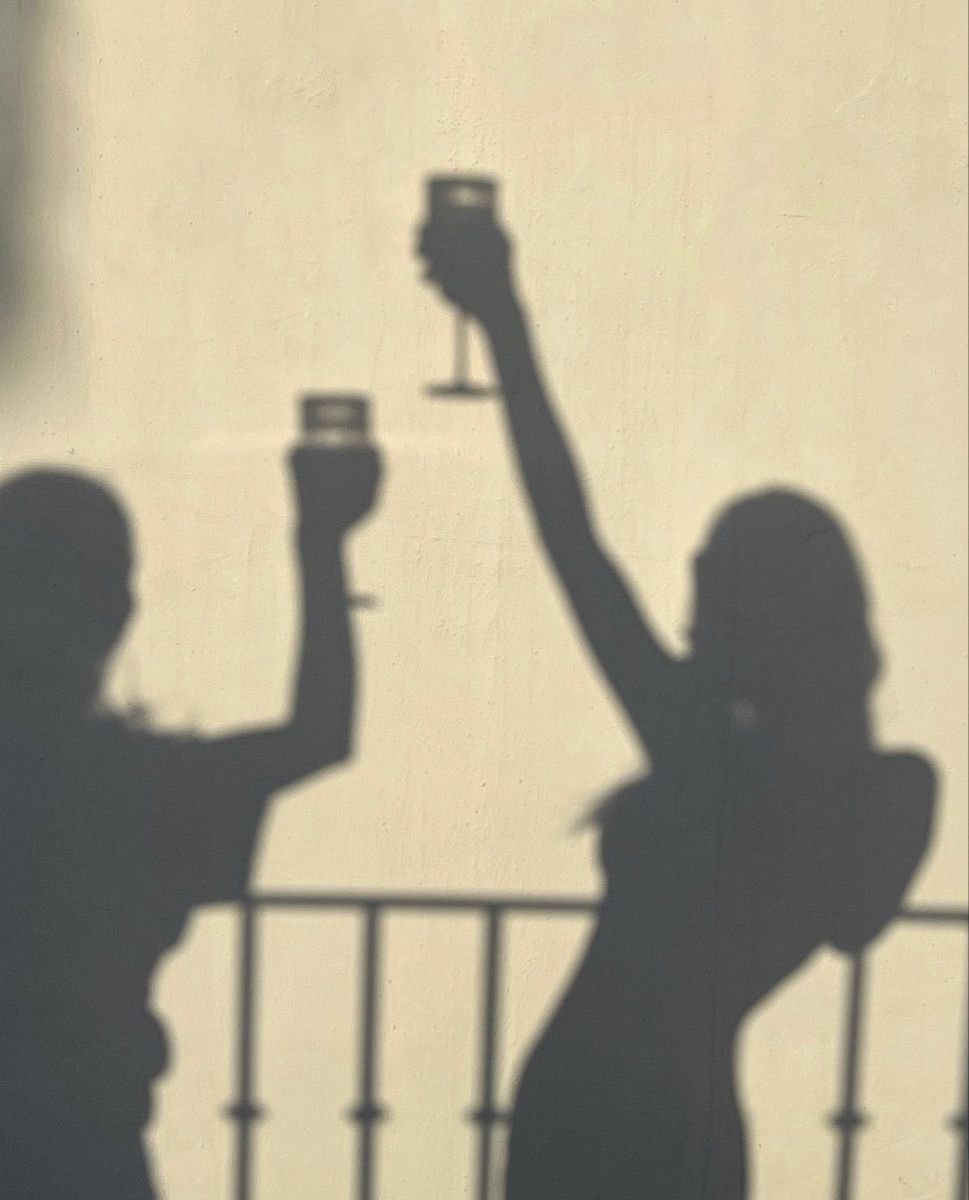 Golden hour shadows of women toasting on a balcony